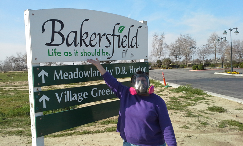 Rosanna in a respirator in front of a Bakersfield's sign Rosanna in a respirator in front of a Bakersfield's sign