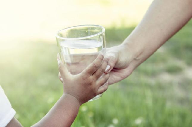 Handing a glass of water to a child. Photo credit: iStock Handing a glass of water to a child. Photo credit: iStock
