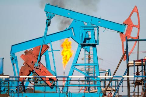 Pump jacks with a methane flare in the background Pump jacks with a methane flare in the background