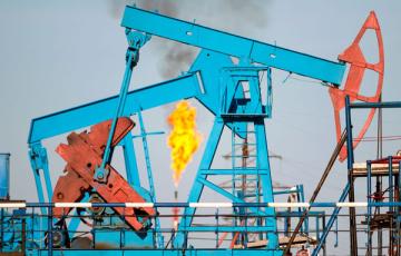Pump jacks with a methane flare in the background