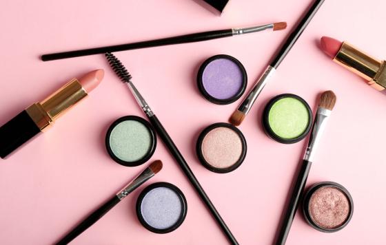 Cosmetics - lipstick, other makeup - arranged on a table. Photo credit: AfricaStudios / Shutterstock